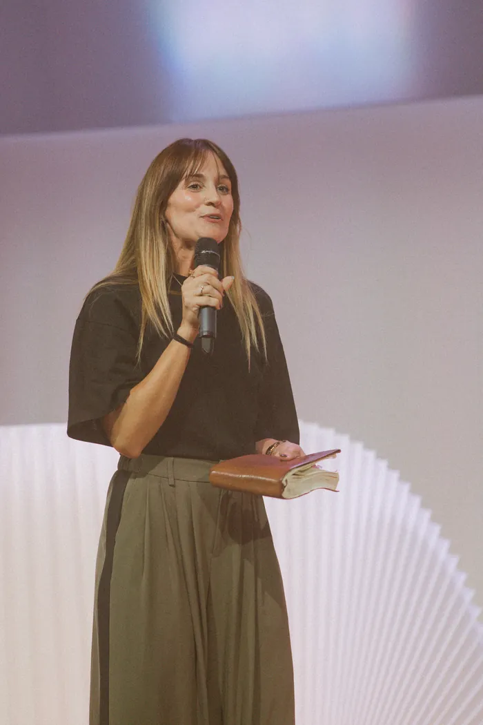 Jess Manuel preaching with a microphone and her Bible in hand