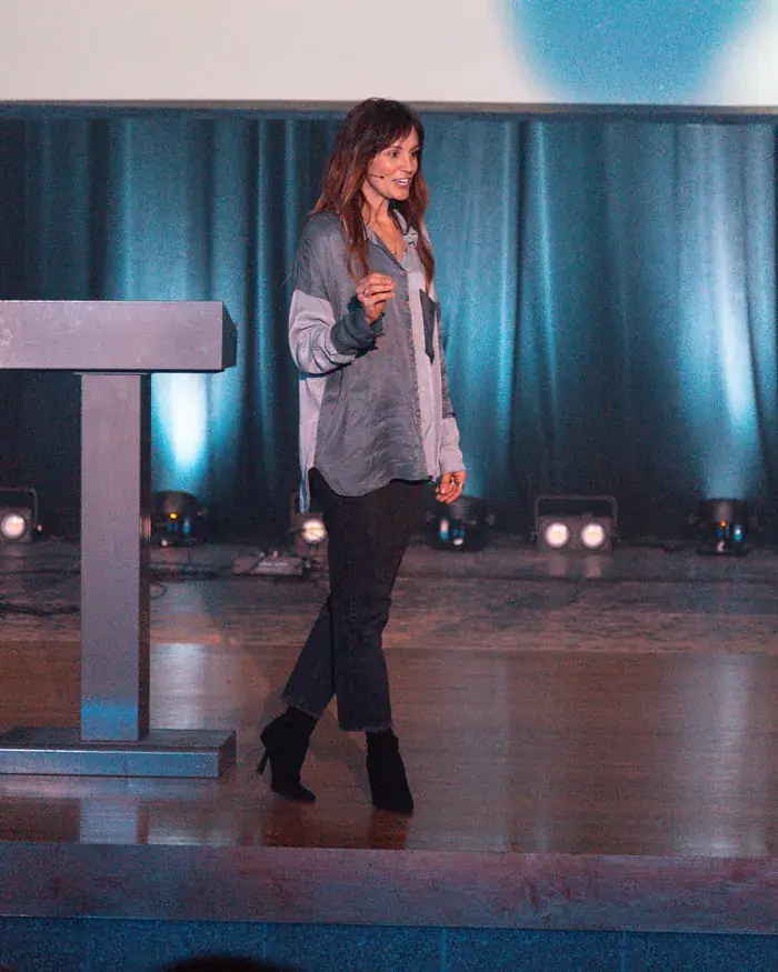Jess Manuel smiling as she walks across the stage while preaching