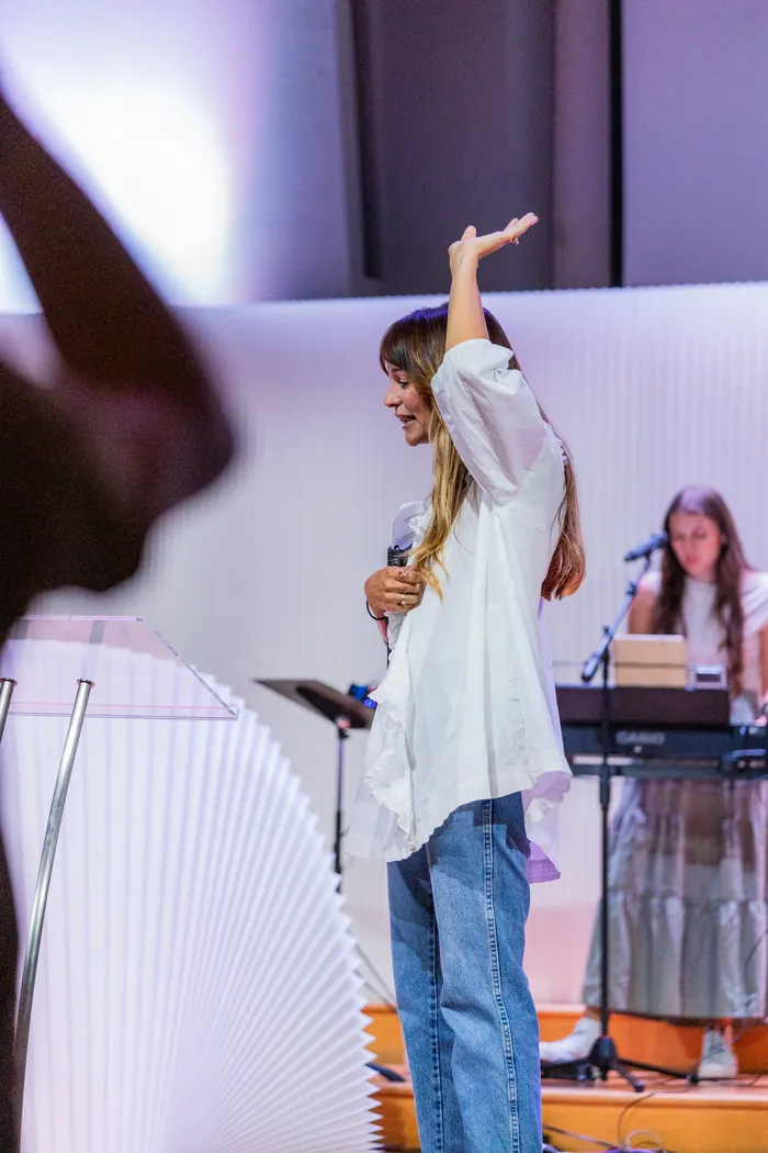 Jess Manuel on stage with one hand raised in worship